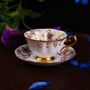Taza de té vintage Royal Albert de porcelana dorada con diseño floral morado y platillo, taza de té festoneada blanca con volutas doradas (década de 1950)