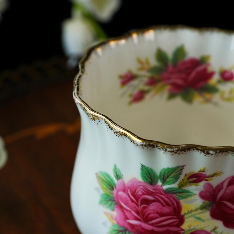 Peut inclure: Un bol en porcelaine blanche avec un bord festonn&eacute; soulign&eacute; d'une peinture dor&eacute;e. Les surfaces ext&eacute;rieure et int&eacute;rieure sont orn&eacute;es d'un motif floral compos&eacute; de roses rose vif, de feuilles vertes et de petites touches jaunes sur fond blanc.