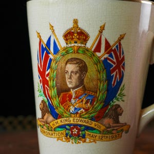Puede incluir: Taza de cer&aacute;mica color crema con un retrato del rey Eduardo VIII, banderas y leones. La taza est&aacute; inscrita con "H.M. King Edward VIII Coronation May 12th 1937". El dise&ntilde;o est&aacute; enmarcado en una corona de laurel.