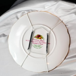Pu&ograve; includere: Piatto decorativo bianco con bordo dorato, con la scritta "Christmas Magic" e un motivo floreale. Include un gancio per piatti in filo metallico con molle nere. Prodotto da Royal Albert.