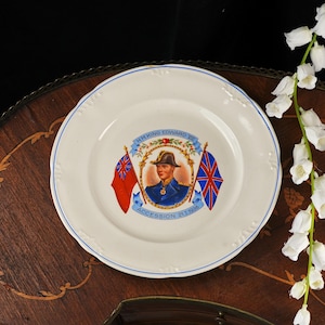K&ouml;nnte beinhalten: Ein cremefarbener Gedenkteller aus Keramik mit einem zentralen Portr&auml;t von H.M. King Edward VIII in Milit&auml;runiform, flankiert von zwei Flaggen, mit dem Text H.M. KING EDWARD VIII und ACCESSION 21.1.1936, verziert mit einem d&uuml;nnen blauen Rand.