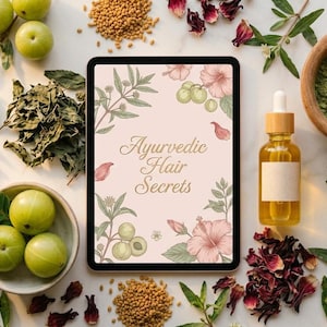 Op de afbeelding: Een bovenaanzicht van Ayurvedische haarverzorgingsingrediënten. Een tablet toont "Ayurvedic Hair Secrets" met bloemmotieven. Andere elementen zijn groene vruchten, kruiden, zaden, een fles olie en een vijzel met groen poeder.