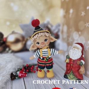 May include: Crochet pattern for a cute elf doll wearing a red and yellow striped outfit with a green hat and a red pom-pom. The doll is standing on a white wooden surface with a red and green Christmas decoration in the foreground. The text "CROCHET PATTERN" is written in black letters on the surface. The flags of Turkey and the United States are also shown on the surface.