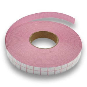 Könnte beinhalten: Eine Rolle rosa Klebeband mit einem Gittermuster am Rand. Das Band ist um einen Pappkern gewickelt. Das Gittermuster ist weiß mit roten Linien. Das Band hat eine hellrosa Farbe.