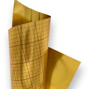 Peut inclure: Un rouleau de vinyle doré avec un motif de grille rouge. Le vinyle est partiellement déroulé, révélant la surface brillante et les lignes de la grille. Le fond est blanc.