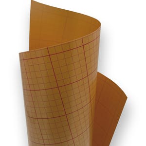 Op de afbeelding: Een rol bruin vinyl met een rood rasterpatroon. Het vinyl is gedeeltelijk uitgerold, waardoor het rasterpatroon zichtbaar is. Het materiaal heeft een glanzende afwerking en wordt gebruikt voor knutselprojecten.