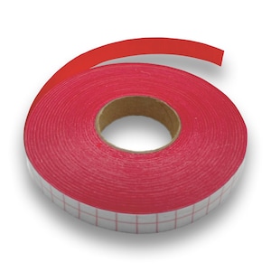 Könnte beinhalten: Eine Rolle leuchtend rotes Klebeband mit einem weißen Gittermuster am Rand. Das Band ist um einen braunen Pappkern gewickelt. Das Ende des Bandes ist sichtbar und zeigt die Klebeseite.