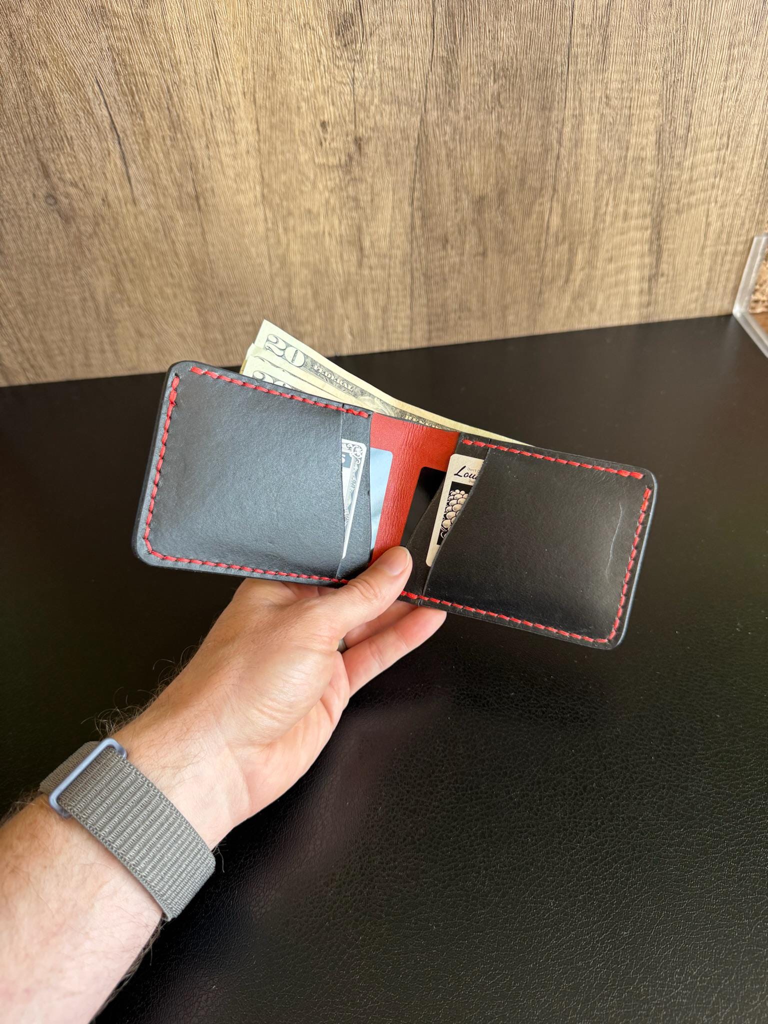 ハンドステッチの二つ折り財布。横型カードポケット。黒と赤のレザーに