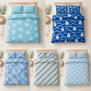 Pode incluir: Uma coleção de cinco conjuntos de roupa de cama com temas náuticos, incluindo padrões de estrelas-do-mar brancas sobre azul claro, veleiros sobre ondas azul-escuras, âncoras brancas sobre azul, riscas diagonais azuis e amarelas e conchas.