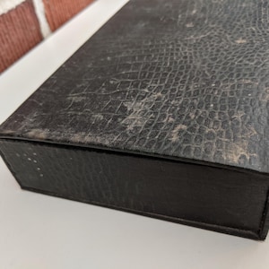 Pu&ograve; includere: Un cartello in legno rustico bianco con la scritta "Welcome" in stile handwritten. Il cartello presenta un aspetto invecchiato e un elemento floreale decorativo. Lo sfondo &egrave; una texture di legno sfocata.