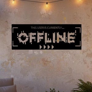 May include: A black metal sign that reads "THIS USER IS CURRENTLY...OFFLINE" hangs on a wall. The sign is on a balcony with a chair, plants, and string lights. A lit candle sits on a small table.