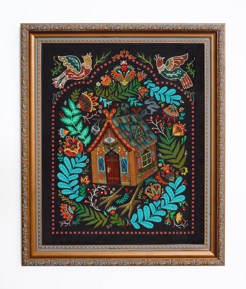May include: A framed folk art print featuring a whimsical house with chicken feet, surrounded by colorful floral and bird motifs. The artwork has a dark background and a decorative gold frame, creating a vibrant and detailed composition.
