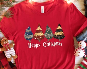 May include: A red t-shirt featuring four Christmas trees in various colors and patterns. The text "Happy Christmas" is printed below the trees. The shirt is styled with jeans, a gift box, socks, and a gingerbread man.