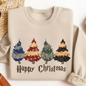 May include: Beige sweatshirt with a festive design featuring four colourful Christmas trees. The trees are in shades of blue, red, green, and black, with decorative elements. The text "Happy Christmas" is printed below the trees.