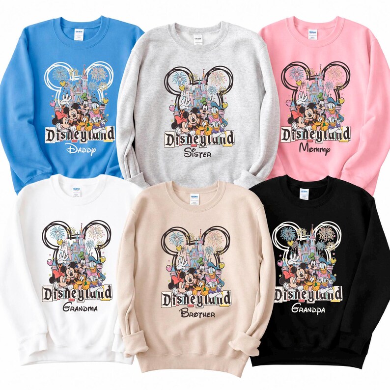 May include: Six crew neck sweatshirts in various colors, including blue, gray, pink, white, tan, and black. Each sweatshirt features a Disneyland graphic with Mickey Mouse and friends, and the words "Daddy", "Sister", "Mommy", "Grandma", "Brother", and "Grandpa".