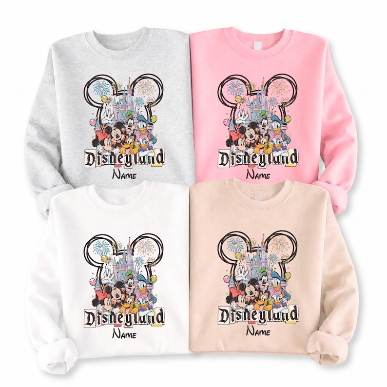 May include: Four sweatshirts in light gray, pink, white, and beige, each featuring a Disneyland graphic. The graphic includes Mickey and Minnie Mouse, Donald Duck, and Goofy, with the Disneyland logo and space for a name.