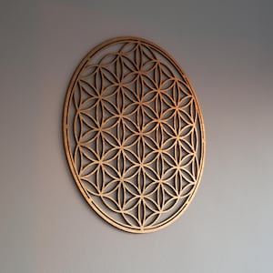 Könnte beinhalten: Eine runde Wanddekoration aus Holz mit einem geometrischen Muster aus überlappenden Kreisen und Dreiecken. Das Muster ist als Blume des Lebens bekannt.