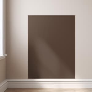 May include: A rectangular section of a wall painted in a dark brown color. The wall is adjacent to a lighter beige wall. A white baseboard runs along the bottom of the walls. A window frame is visible on the left side.