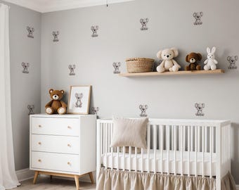 May include: A nursery with a white crib, dresser, and a floating shelf. The crib has a beige skirt and a matching pillow. The dresser has three drawers and wooden knobs. The wall is decorated with koala bear decals and a framed koala bear print. Stuffed animals are on the shelf.