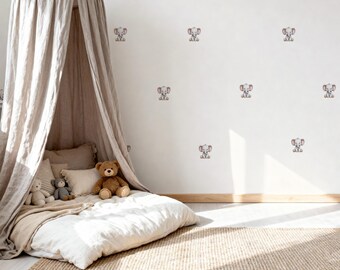 May include: A cozy children's bedroom scene featuring a beige canopy bed with pillows and stuffed animals. The white wall is adorned with elephant decals. A woven rug covers the floor, creating a warm and inviting space.