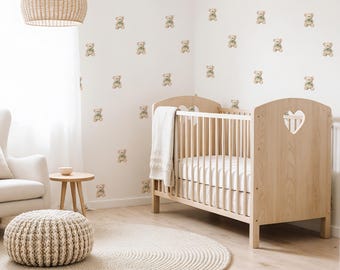 May include: A nursery room with a light wood crib, a white armchair, and a round rug. The walls are decorated with teddy bear decals. A woven pendant light hangs from the ceiling, and a small side table and ottoman complete the scene.