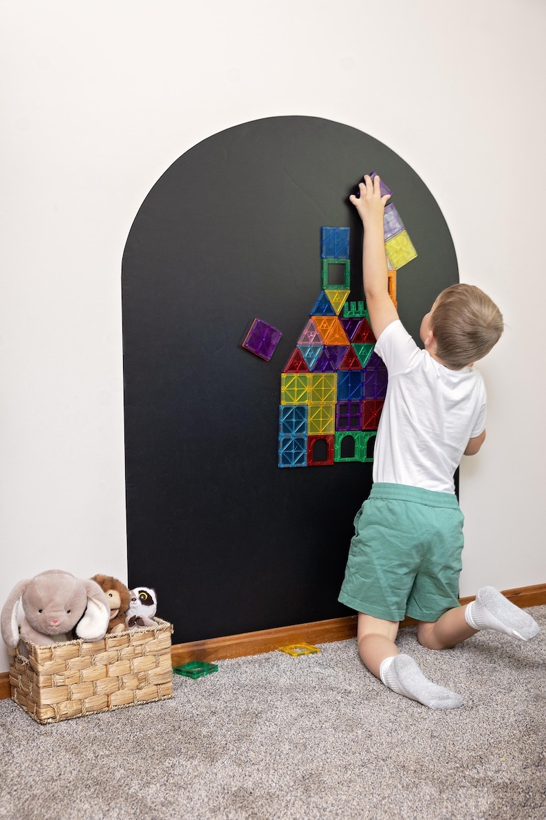 May include: A large arched black wall decal featuring a collection of colorful, translucent magnetic building tiles arranged in a house-like structure. The tiles are square and triangular in shades of red, blue, green, orange, purple, and yellow.
