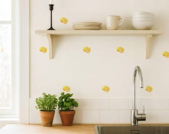 May include: A bright kitchen scene with a wooden countertop, white cabinets, and a stainless steel sink. The white wall features lemon slice decals. A shelf holds dishes and a mug. Two potted herbs sit on the counter.