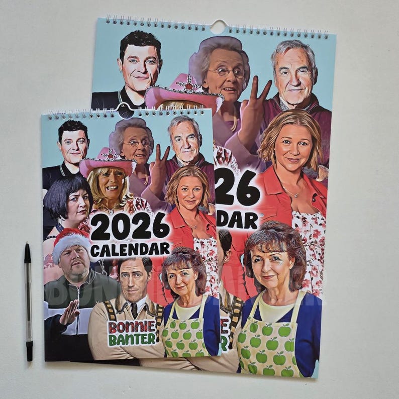 May include: Two 2026 calendars with a spiral binding and a hole for hanging. The calendars feature a collage of portraits of people. The text "2026 CALENDAR" is visible on the smaller calendar. A black pen is on the left.