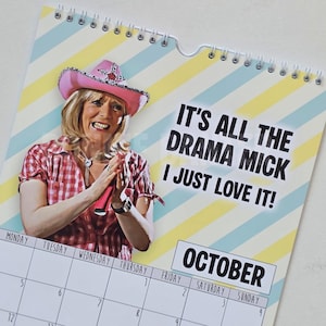 May include: A wall calendar with a woman wearing a pink cowboy hat and a red plaid shirt. The calendar has the text "IT'S ALL THE DRAMA MICK I JUST LOVE IT!" and the month of October is displayed.