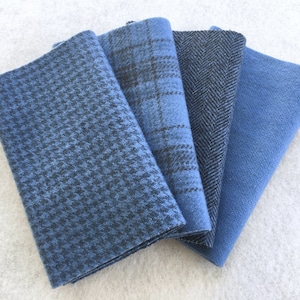 Peut inclure: Quatre échantillons de tissu pliés en nuances de bleu. Les motifs comprennent pied-de-poule, carreaux, chevrons et uni. Les tissus sont probablement de la laine ou un mélange de laine, pour vêtements ou décoration.