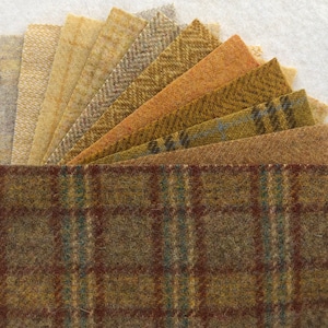 May include: A collection of 12 wool fabric squares in various shades of brown, beige, and gray. The squares are arranged in a fan shape, with the largest square at the bottom and the smallest square at the top. The fabric has a variety of textures, including smooth, textured, and patterned.