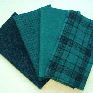 May include: Four teal fabric swatches with different textures are fanned out. The textures include a herringbone pattern, a small houndstooth pattern, a solid color, and a plaid design. The fabrics are a deep teal color.