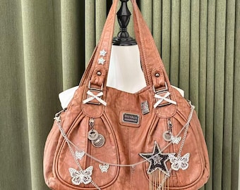 May include: A brown leather handbag with decorative butterfly and star accents. The bag features silver chains, charms, and a rectangular label that reads "OUYALU". The bag has two handles and a large main compartment.