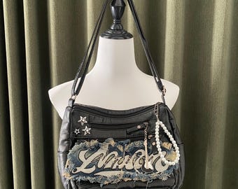 May include: Black faux leather shoulder bag with a denim patch featuring the word "Love" and stars. The bag has a silver chain and a pearl necklace attached.