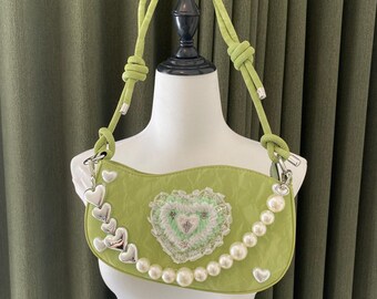 Peut inclure: Un sac à main matelassé vert lime avec un motif en forme de cœur et un détail de charme en perles et en cœur.