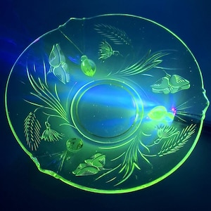 Può includere: Una ciotola di vetro verde vintage con un motivo floreale. La ciotola è in vetro all'uranio e brilla sotto una luce nera.