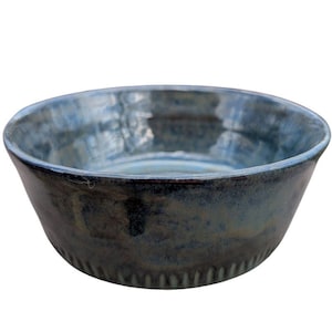 May include: A blue ceramic bowl with a textured rim. The bowl has a dark blue glaze with a light blue sheen.
