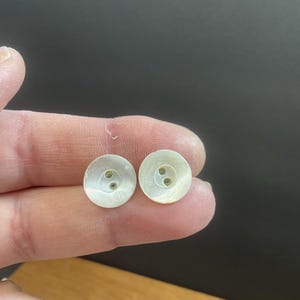 Puede incluir: Dos botones blancos de madreperla con dos agujeros cada uno.