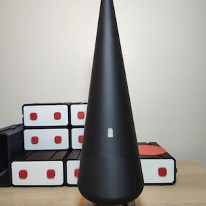 May include: A black cone-shaped object with a silver base and three legs. The object has a small, rectangular, silver button on the front.