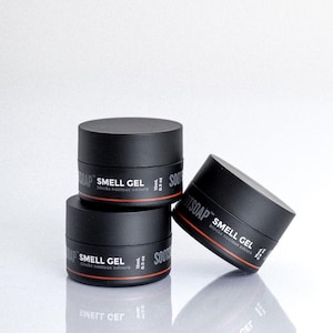 Könnte beinhalten: Drei schwarze Gläser Soothsoap Smell Gel, jedes mit dem Produktnamen und "blocks noxious odours" beschriftet. Die Gläser sind jeweils 0,5 oz (15 ml) groß.