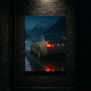 May include: A framed print of a silver coupe driving on a wet road at night. The car's taillights glow red, reflecting on the asphalt. Snow-covered mountains are visible in the background under a dark, cloudy sky. The print is mounted on a brick wall.