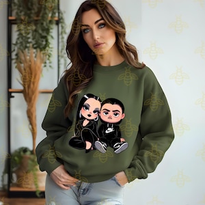 May include: A green sweatshirt with a cartoon illustration of a couple. The woman has long black hair and is wearing a black dress. The man has short black hair and is wearing a black jacket with a white Nike logo.