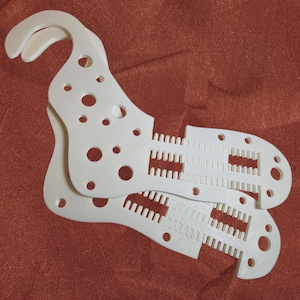 May include: Two white plastic shoe inserts with a series of holes and a textured pattern on the bottom.