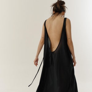 May include: A black sleeveless maxi dress with a low back and a tie at the waist.