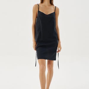 May include: A black sleeveless dress with a scoop neck and adjustable straps. The dress is made from a lightweight fabric and has a relaxed fit.