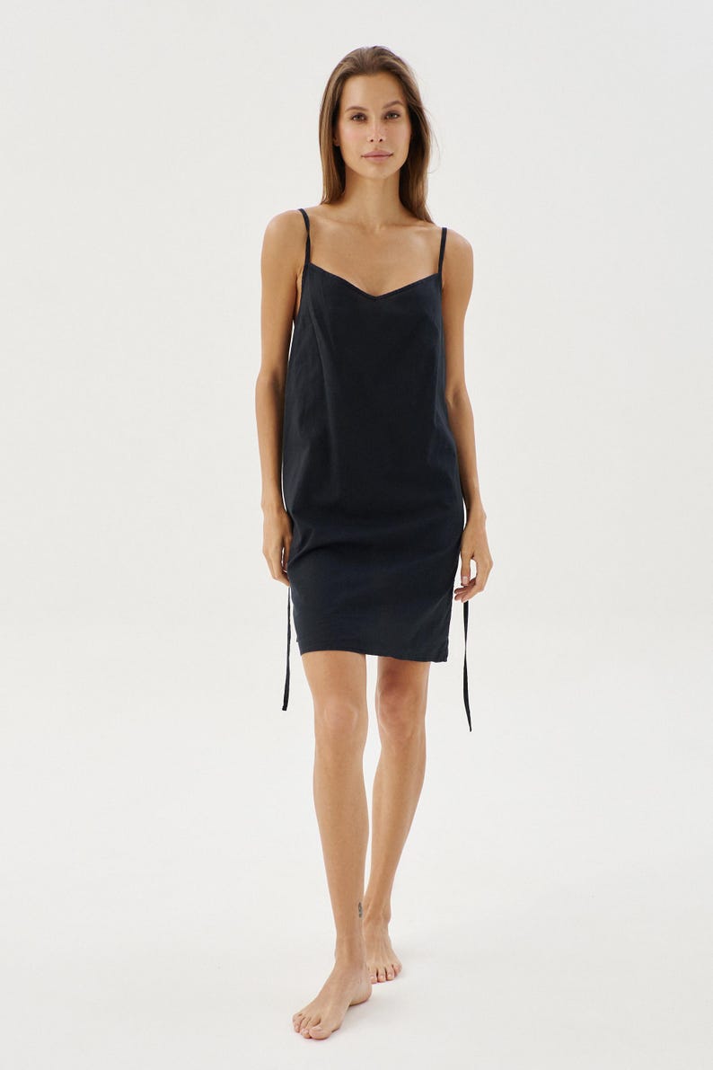 May include: A black sleeveless dress with a scoop neck and adjustable straps. The dress is made from a lightweight fabric and has a relaxed fit.