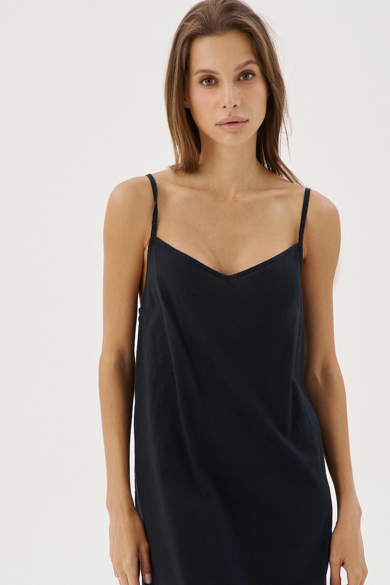 May include: A black sleeveless dress with a V-neckline. The dress is made of a soft, flowing fabric.