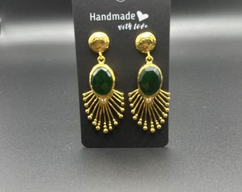 May include: Gold dangle earrings with a green gemstone and a gold textured top. The earrings are displayed on a black card with the text "Handmade with love".