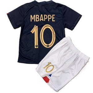 May include: A dark navy blue short-sleeved jersey featuring the name MBAPPE and the number 10 in gold lettering on the back. Paired with white athletic shorts that also display the number 10 in gold on the front leg and red and blue accents.