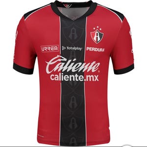 May include: Red and black short-sleeved soccer jersey with the word "Caliente" in white across the front. The jersey has a black vertical stripe down the center and the team logo on the chest. The sleeves and collar are black.